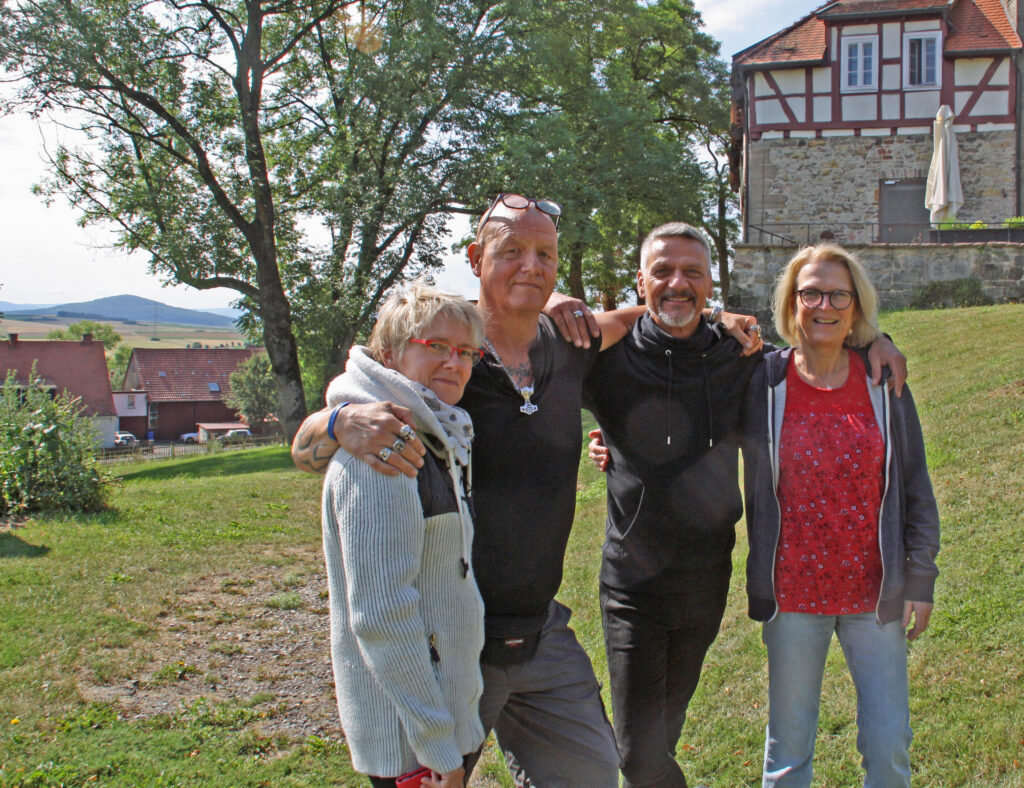 Vier SoberGuides stehen Arm in Arm im Freien und lächeln in die Kamera.